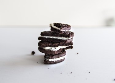 Stacked Oreo cookies with a bite taken out of each on a white surface.