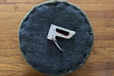 Gray felt circle stapled on top of wood circle to hide unfinished fabric edge