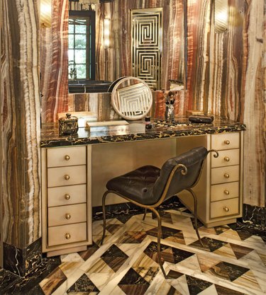 Hollywood regency black, ivory and gold bathroom with makeup vanity and stone tile floor in blacks, browns and creams.