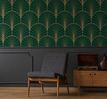 Room with a grey chair and art deco green and gold wallpaper