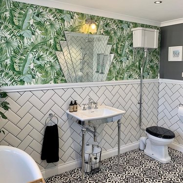 A twenties inspired bathroom with bold print wallpaper and geometric vintage mirror