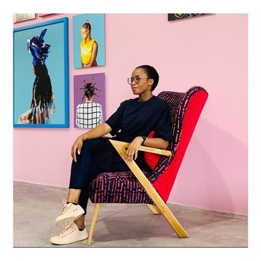 Furniture designer Tosin Oshinowo sitting in a colorful chair with wood legs