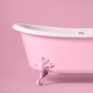 A Pink Champagne colored bathtub in front of a pink wall.