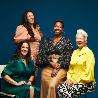 4 women smiling at camera with teal backdrop