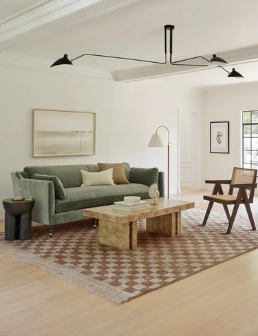 living room with checkered rug and sage green sofa
