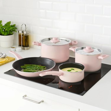 stovetop with four pink cookware dishes