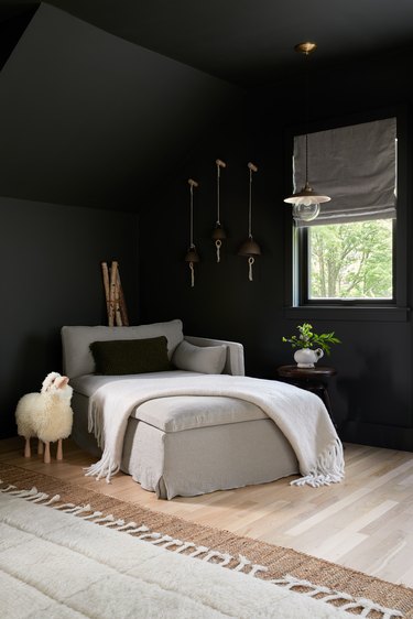 sitting area in a bedroom with dark walls and a sheep decor object