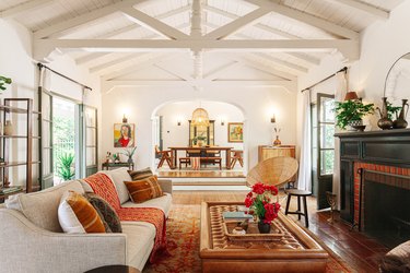 Ranch style living room with white vaulted ceiling, eclectic furniture and textiles, and wood floor