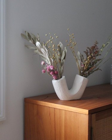ceramic vase with flowers on a wooden furniture piece