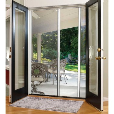 A French door with screen doors attached leading to a backyard
