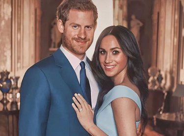 Prince Harry in a navy blue suit next to Meghan Markle in a powder blue dress.