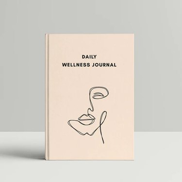 notebook with text that reads "daily wellness journal" and an illustration of a face