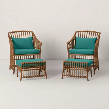 two wicker patio chairs with separate foot rests and teal cushions