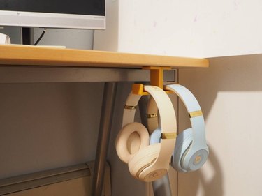 corner of desk with two pairs of headphones hanging