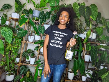 A Black woman with curly, shoulder-length black hair wearing a T-shirt that says "melanin gives you super powers."