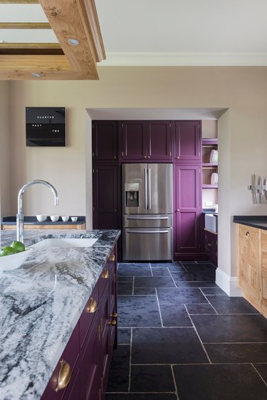 Kitchen with stainless steel fridge, purple cabinets, and blue tiled floors.