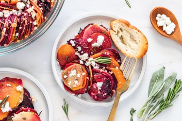 A piece of the root vegetable and goat cheese bake on a white plate on a marble countertop.