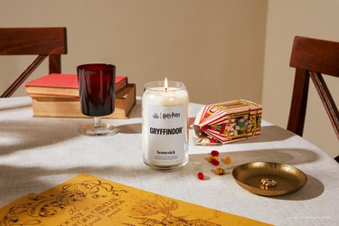 The Homesick Gryffindor candle on a white dining table with a box of Bertie Bott's Every Flavor Beans.