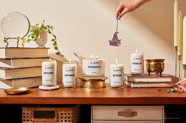 Five of the Homesick Harry Potter candles on a wood table with books and a crystal ball.