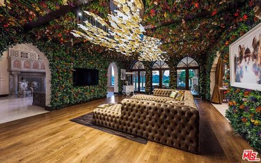 A living room with tufted couch and ivy all over the walls and ceiling