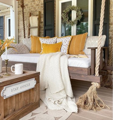 hanging porch swing with golden pillows and knit throw
