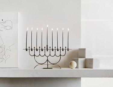 A stainless steel menorah on a mantelpiece with light gray blocks.