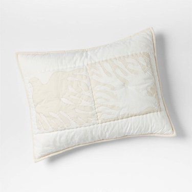 A white and cream pillow sham features a pair of Lucia Eames' soaring doves.