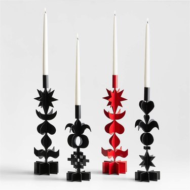 Three black and one red candle holders featuring stacked hearts, stars, circles, moons, and other Lucia Eames graphics.