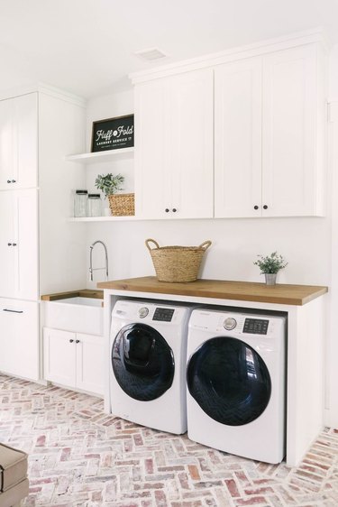 Laundry room with farmhouse sink, cabinets and butcher block countertops.