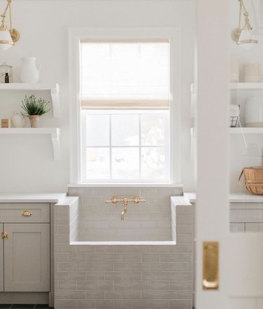Laundry room with tiled sink and gold fixture.