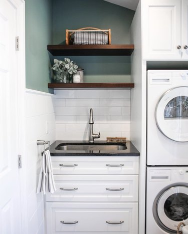 Laundry room with stackable washer and dryer and utility sink.