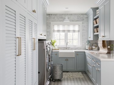 Laundry room with light blue cabinets, white counters and farmhouse sink.