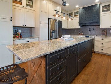 Kitchen with quartz counter on island, white cabinets, black cabinets.
