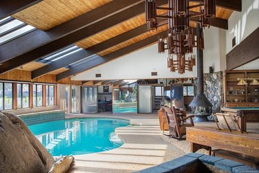 Living room with high ceilings a fireplace and an indoor pool off to the side.