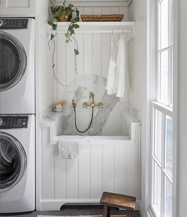 Laundry room with deep sink, handheld sprayer and marble backsplash.