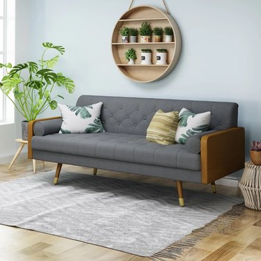 Grey tufted couch with wooden accents