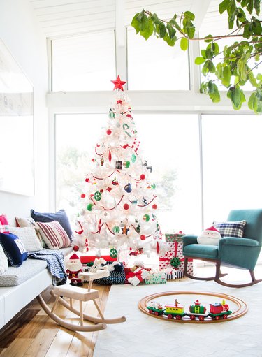 White Christmas tree in a modern living room with floor to ceiling windows