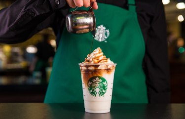 starbucks employee pouring chocolate on drink in cup