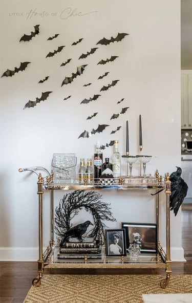 Gold bar cart with bats on the wall.
