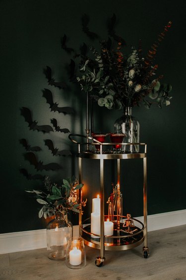 Small bar cart with two red drinks on top and candles below.