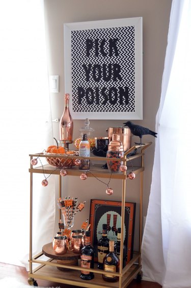 Bar cart with pick your poison sign above it.