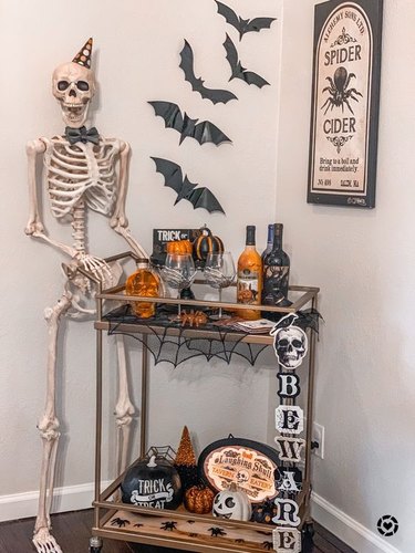Bar cart being pushed by a skeleton.