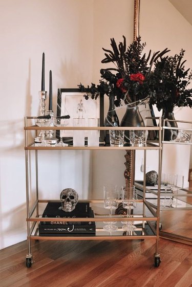 Bar cart with dark flowers and candle.