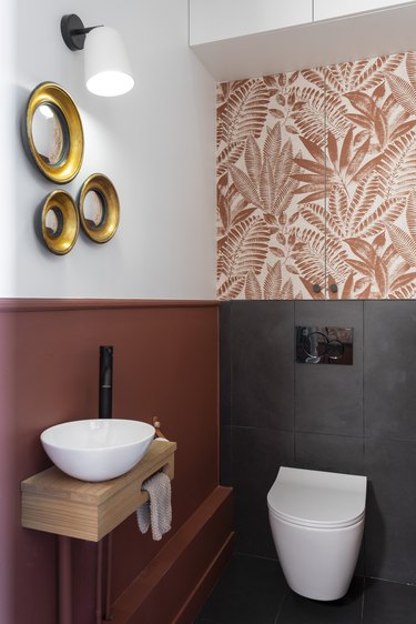 A bathroom with wallpaper and black tiles.