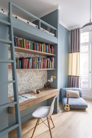 A kid's room with a lofted bed and built-in desk.