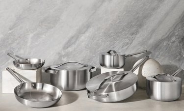 stainless steel cookware set staged in front of gray backdrop