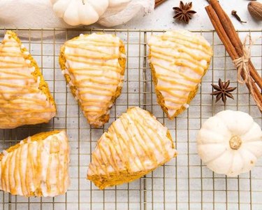 Triangle pumpkin scones on a cooling rack on a white countertop.