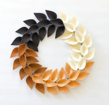 A wreath made out of white black and brown felt leaves