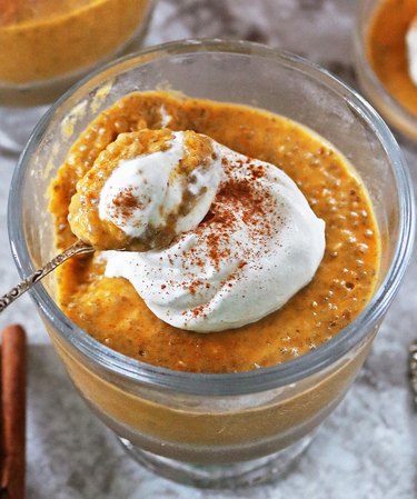 A top view of a glass cup filled with pumpkin spice chia pudding topped with whipped cream.