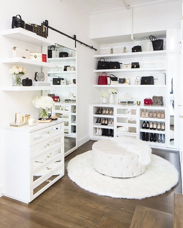 white walk-in closet with open shelving and sliding mirror
